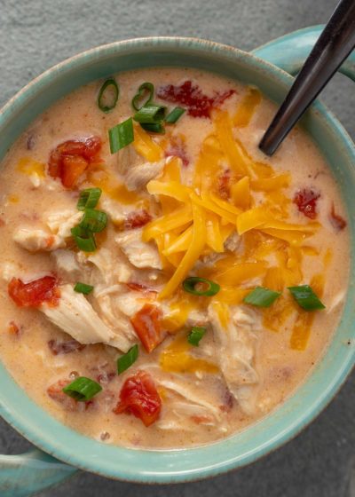 an overhead shot of chicken soup with cheese and rotel with a spoon