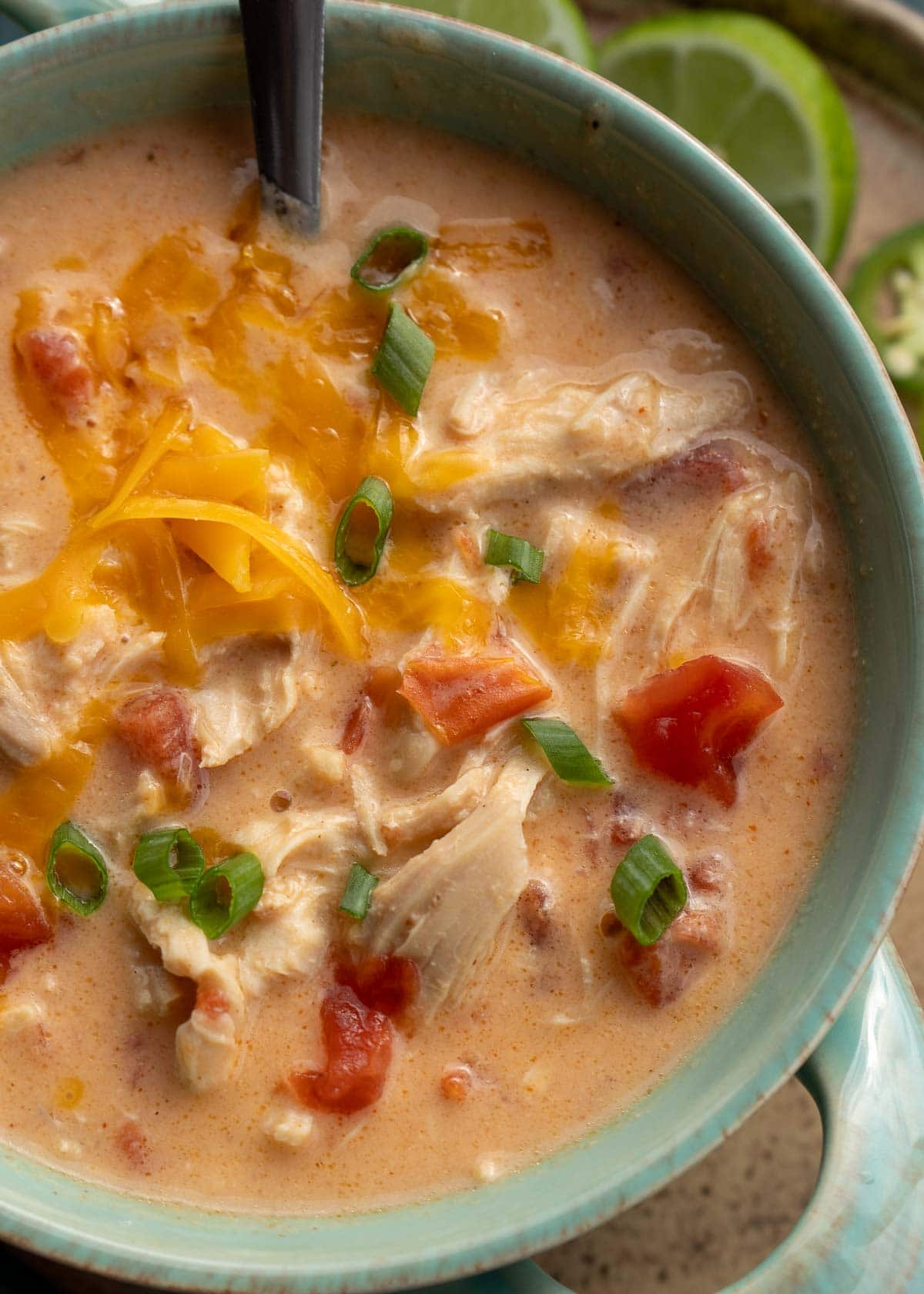 An overhead shot of cheesy rotel chicken soup in a blue bowl with a spoon