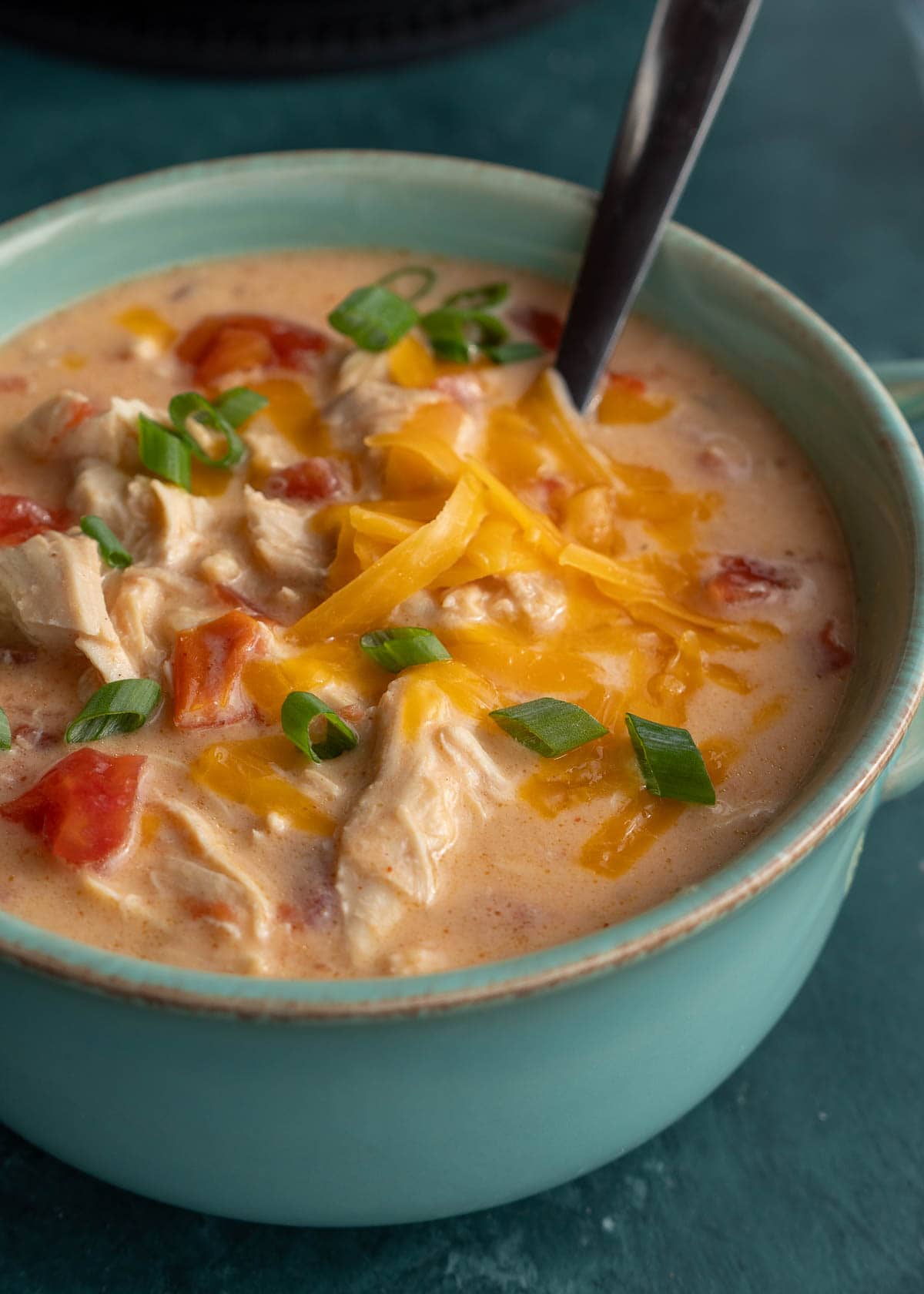 a bowl of chicken soup with cheese and rotel tomatoes
