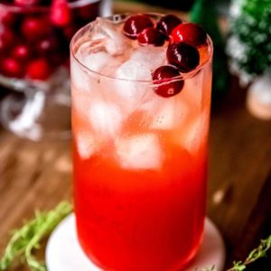 cranberry spritz in a tall glass with ice and cranberry garnish