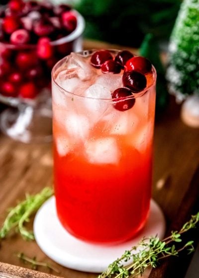 cranberry spritz in a tall glass with ice and cranberry garnish