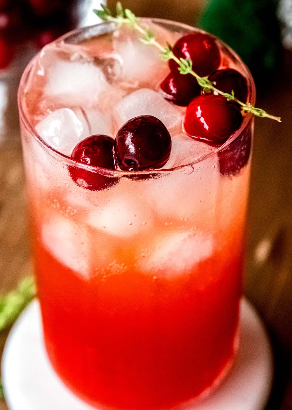 closeup of cranberry spritz, garnished with cranberries and thyme