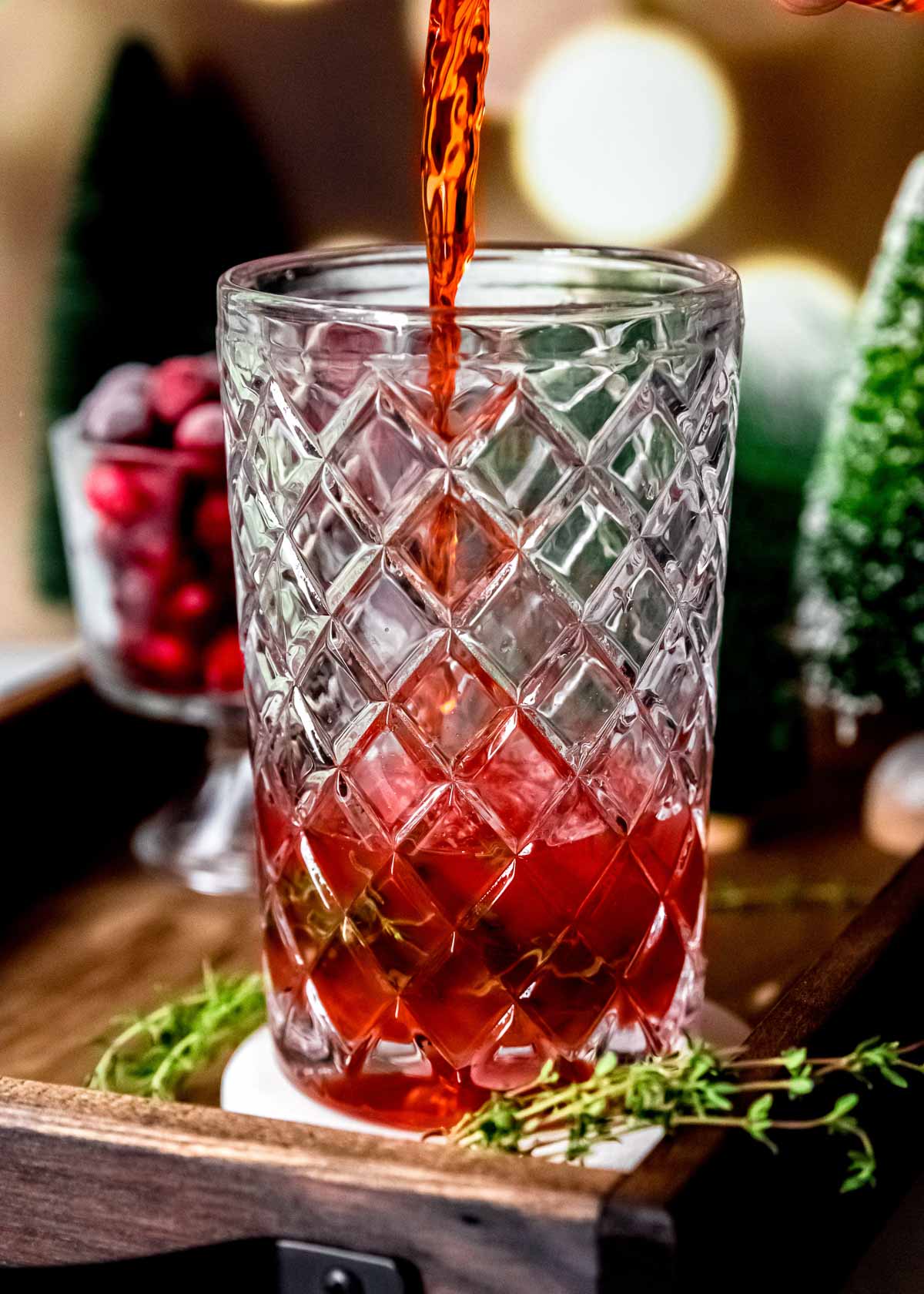 cranberry juice being poured into a shaker