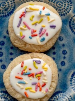 two iced keto sugar cookies on a blue plate