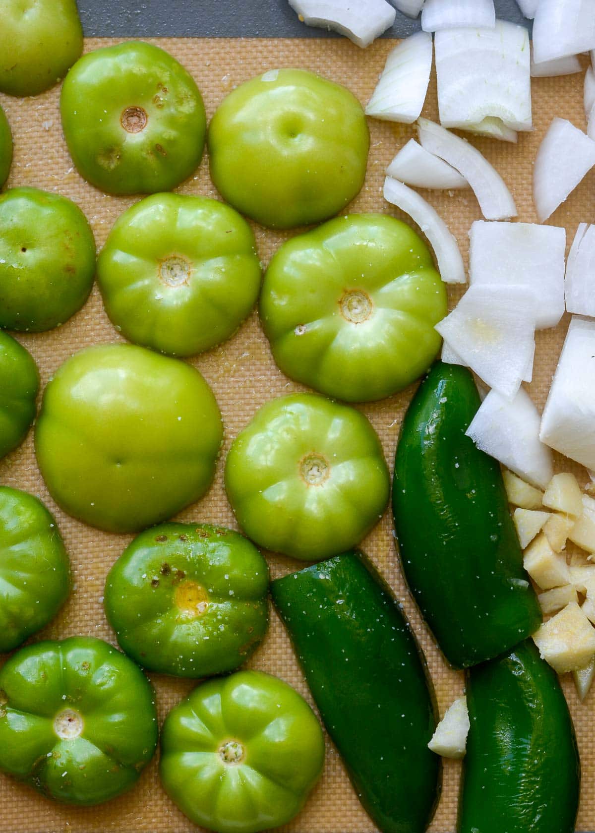 tomatillos, jalapeno, and onion on a silicone lined sheet pan