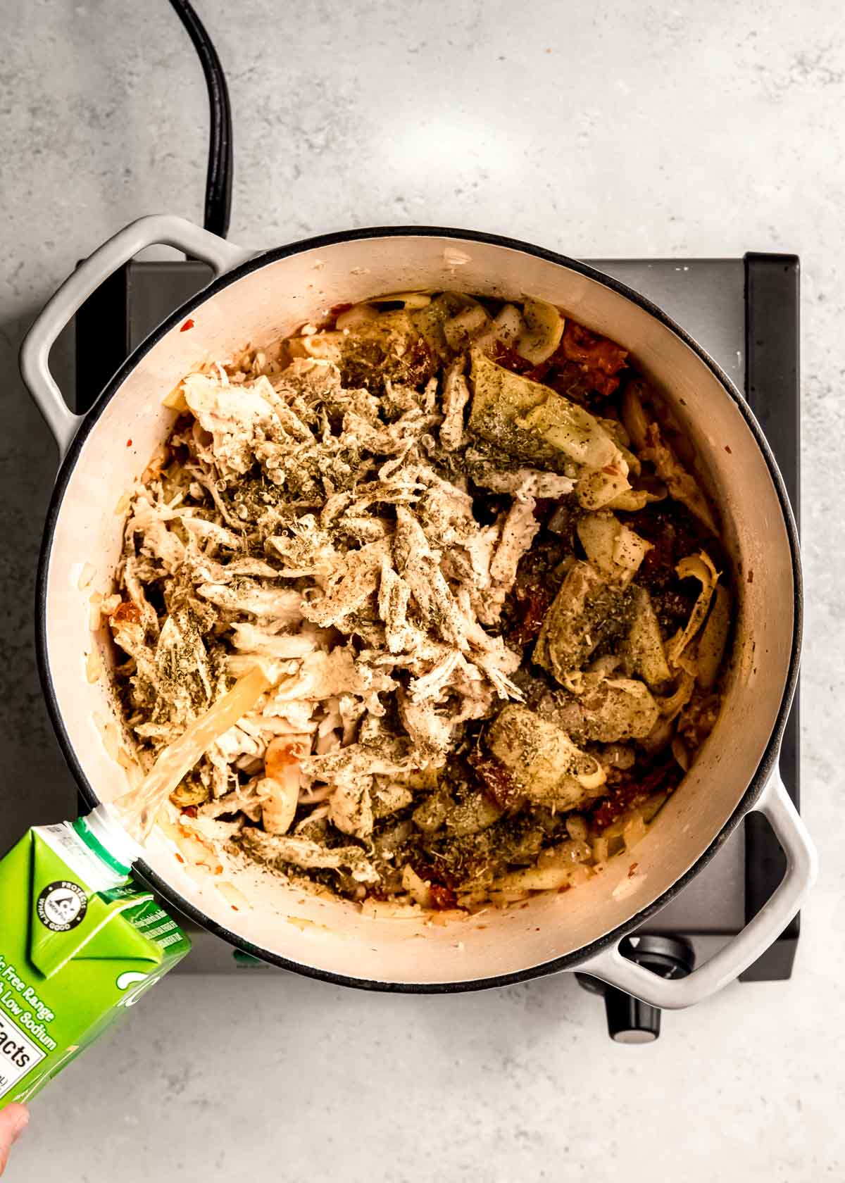 chicken and spices being added to tuscan chicken in dutch oven