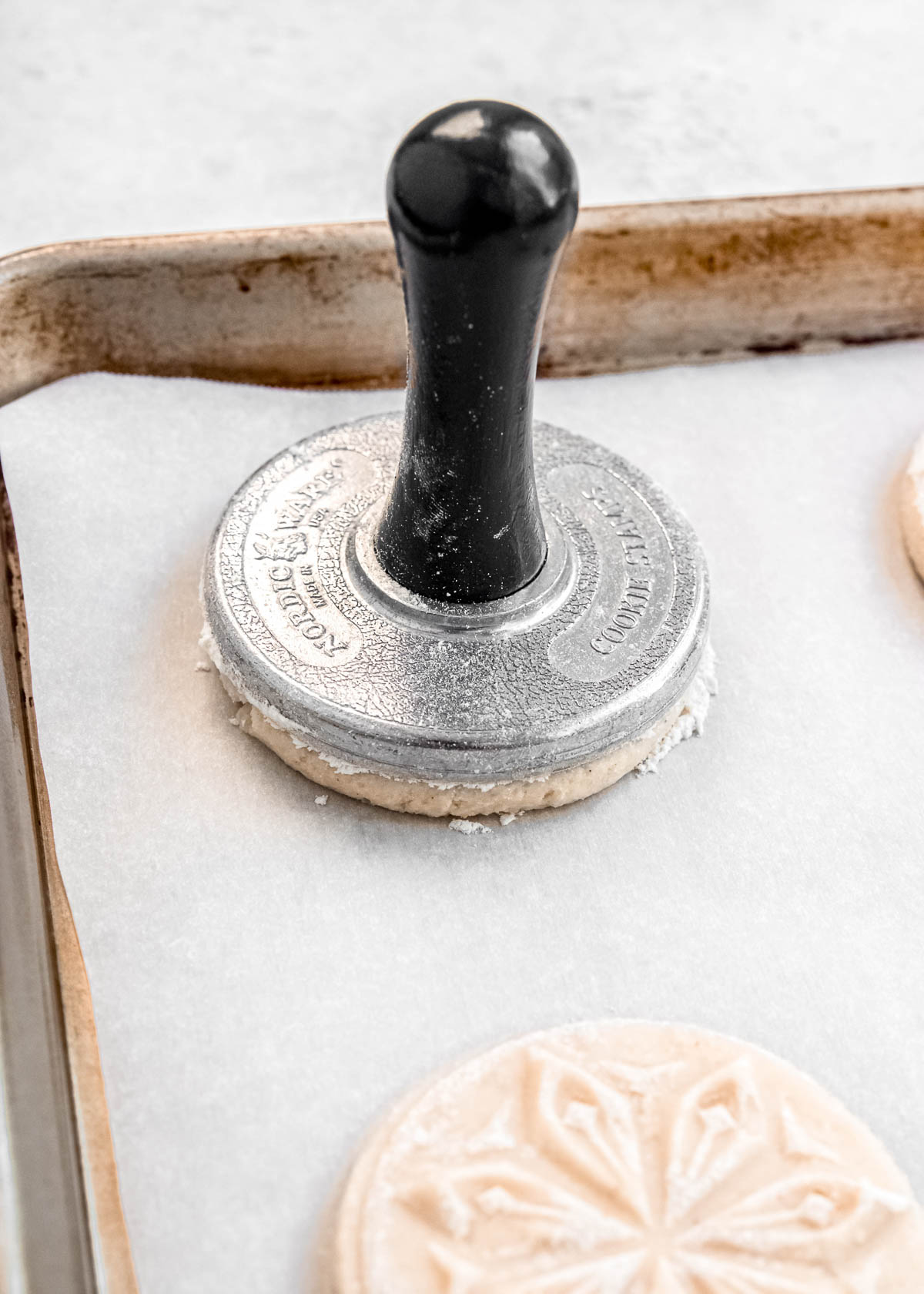 cookie being stamped on a baking sheet