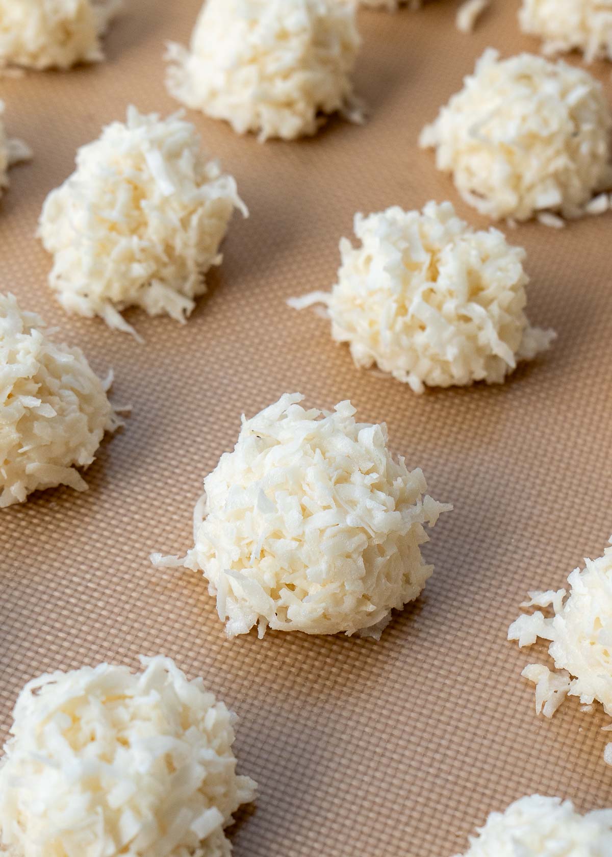 macaroons being shaped and added to cookie sheet