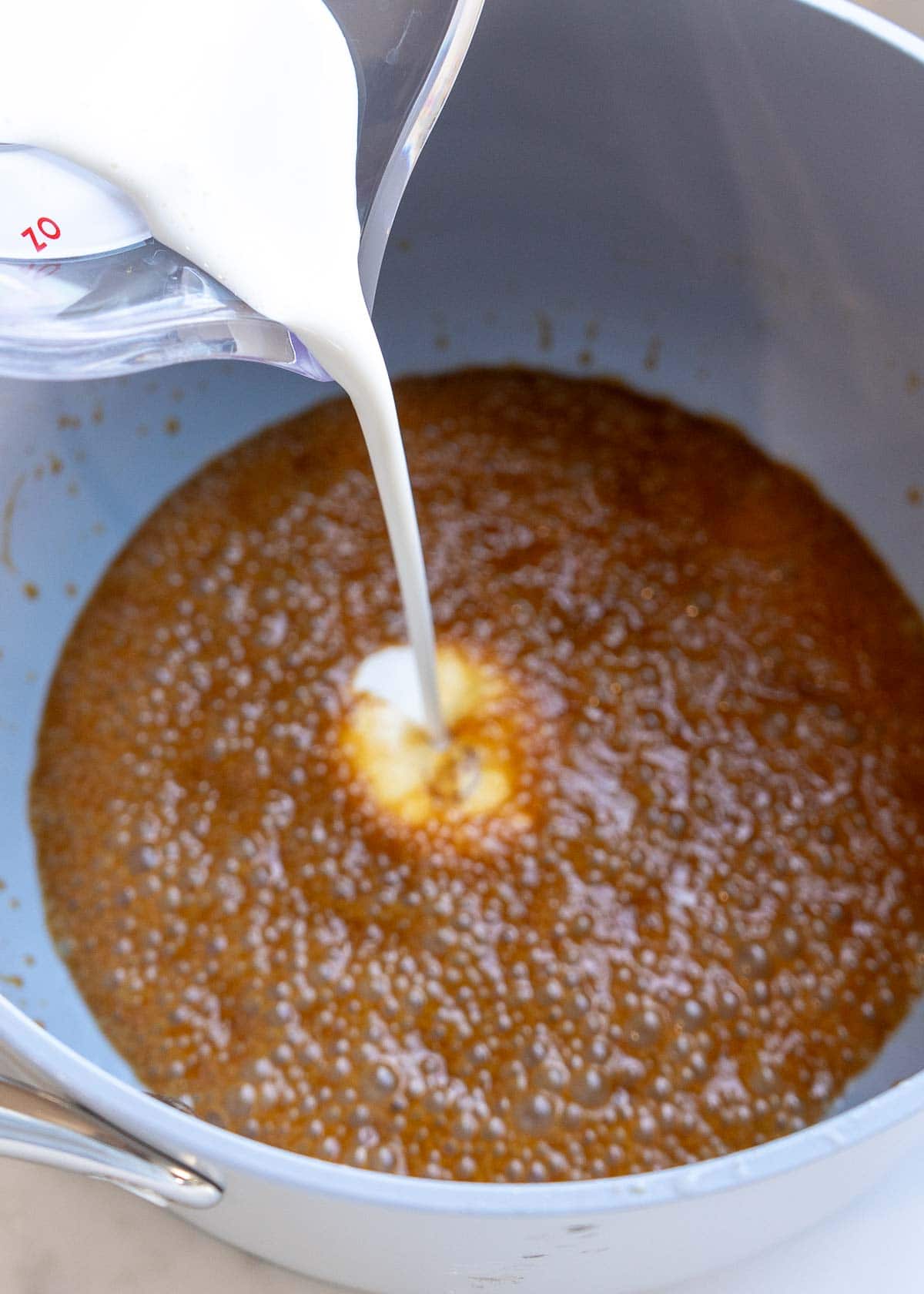 heavy cream being poured into browned sweetener and butter