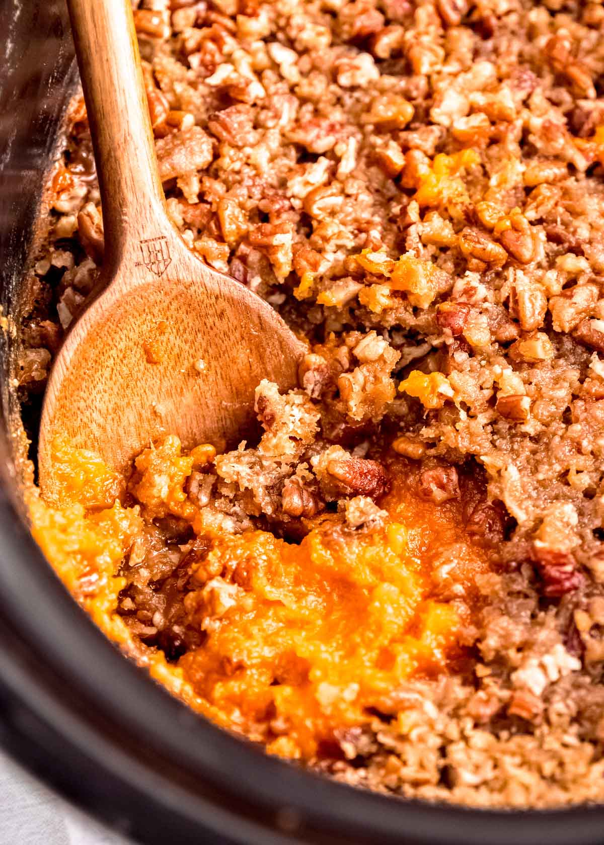 a slow cooker with sweet potato casserole with a brown sugar pecan topping