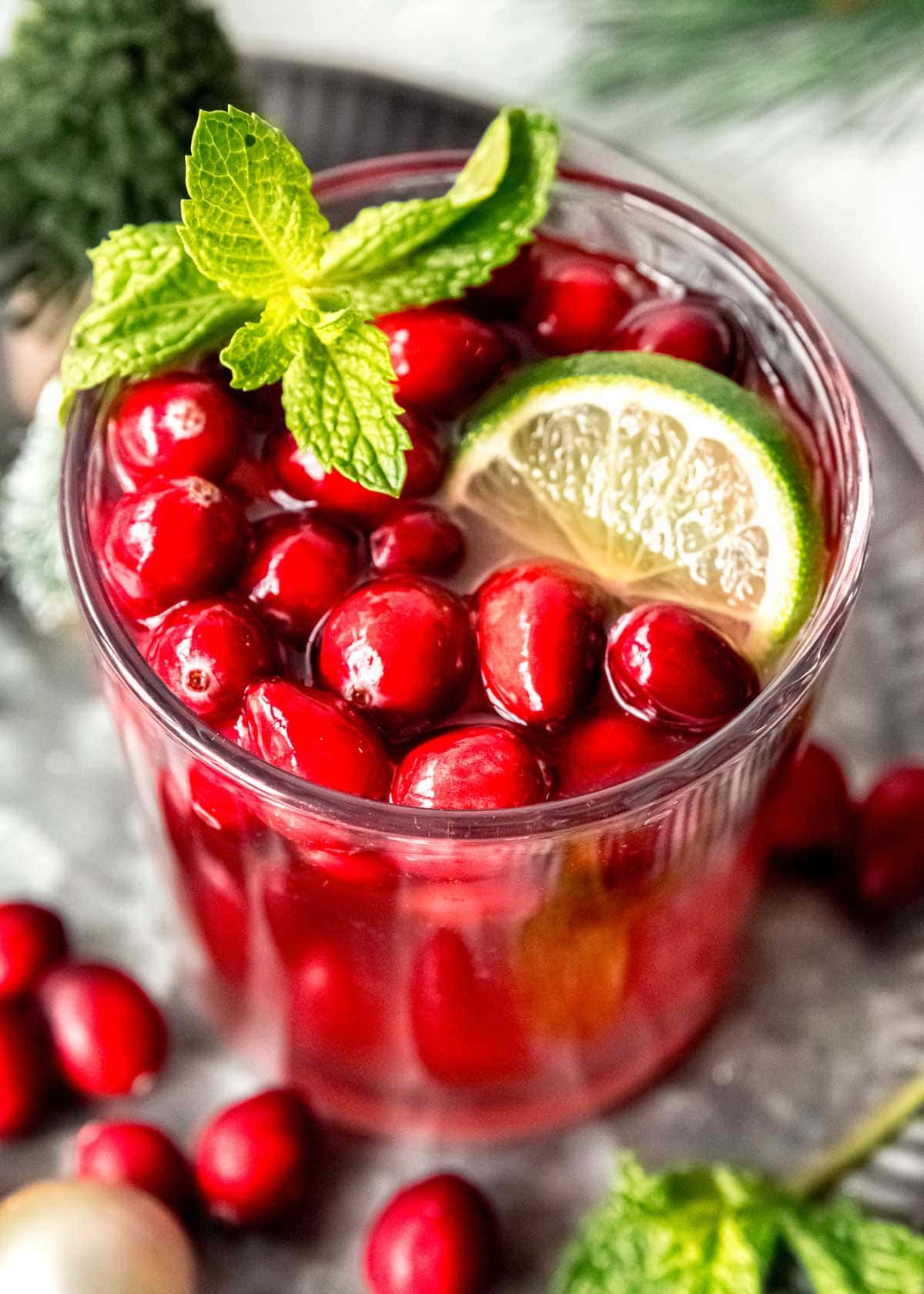 closeup view of glass of Christmas Punch garnished with mint, lime, and berries