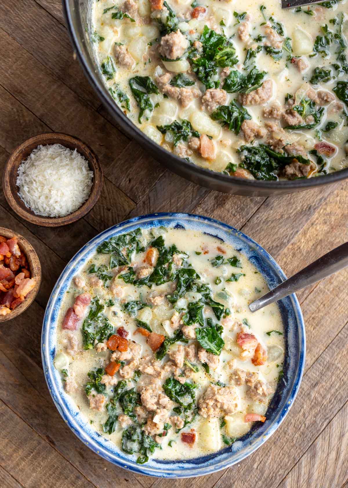 a pot full of zuppa toscana beside a big bowl of the best olive garden copycat soup