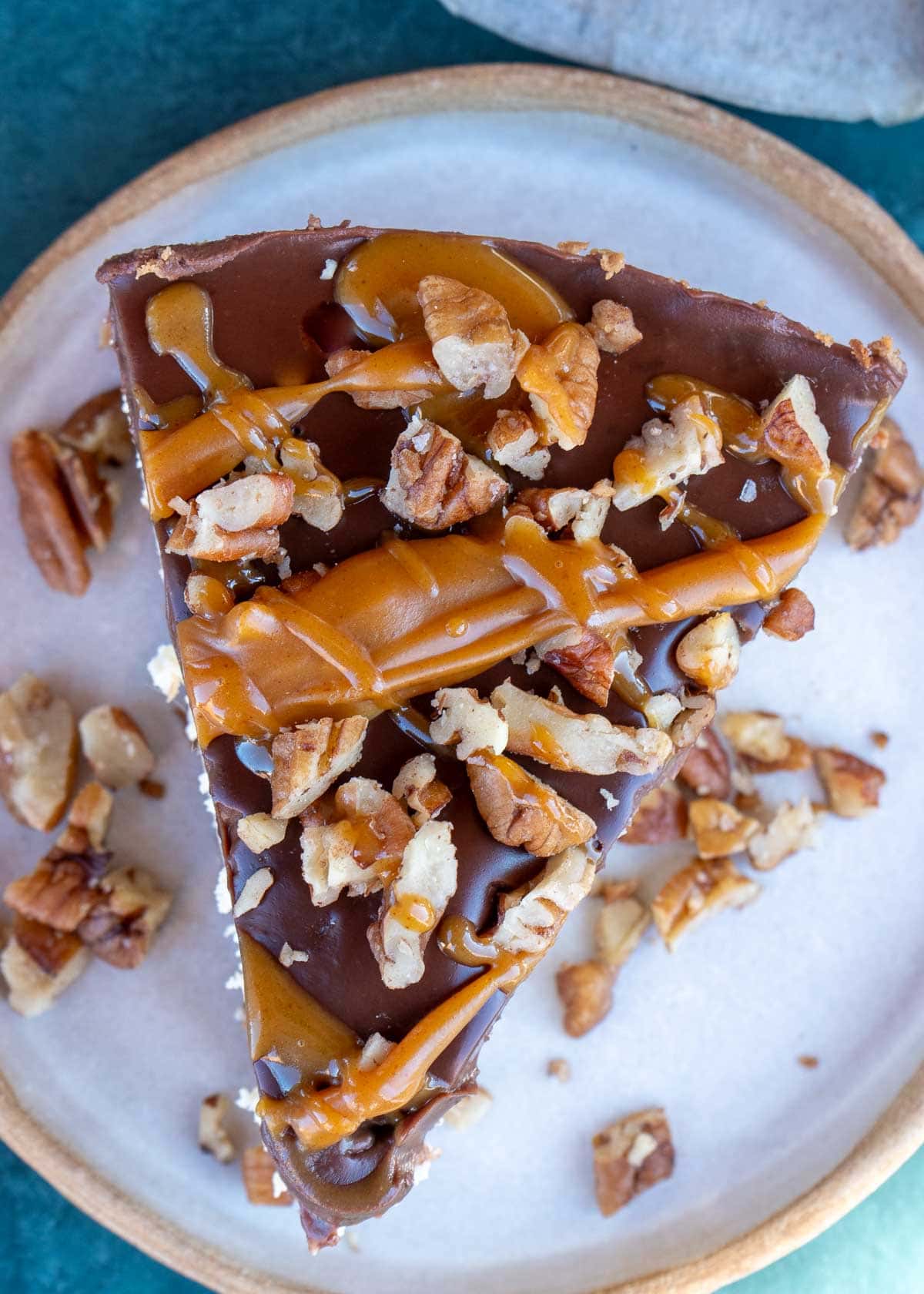 a close up shot of a slice of turtle cheesecake on a white plate