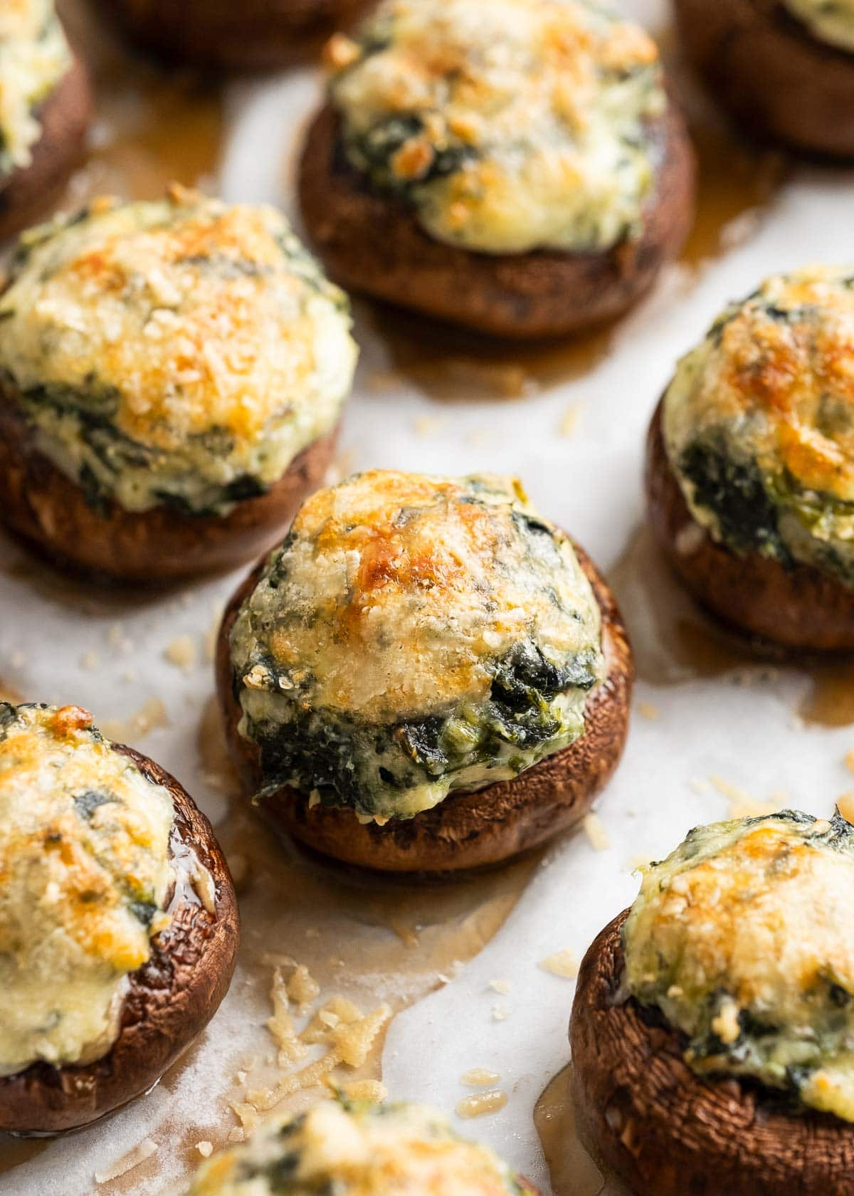 cheesy spinach stuffed mushrooms on a parchment paper lined baking pan