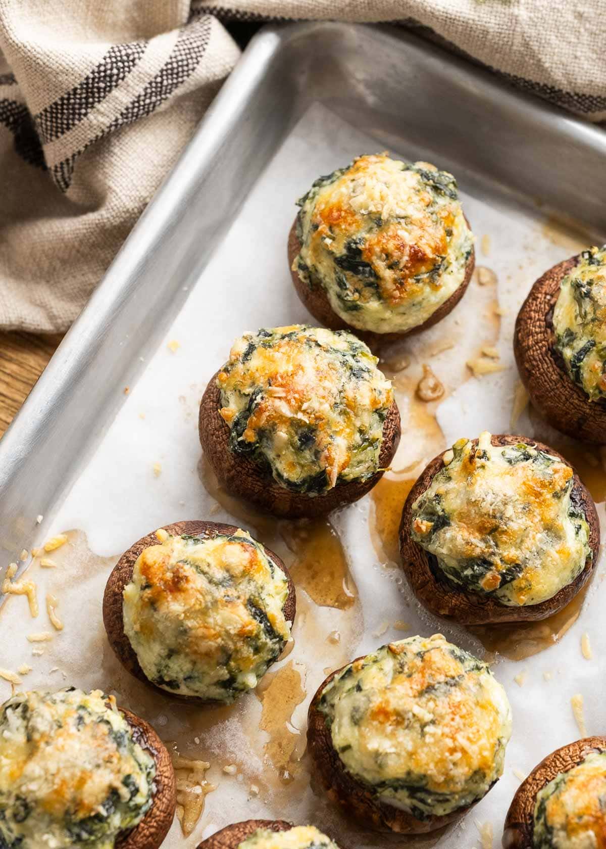 spinach stuffed mushrooms on a baking sheet lined with parchment paper