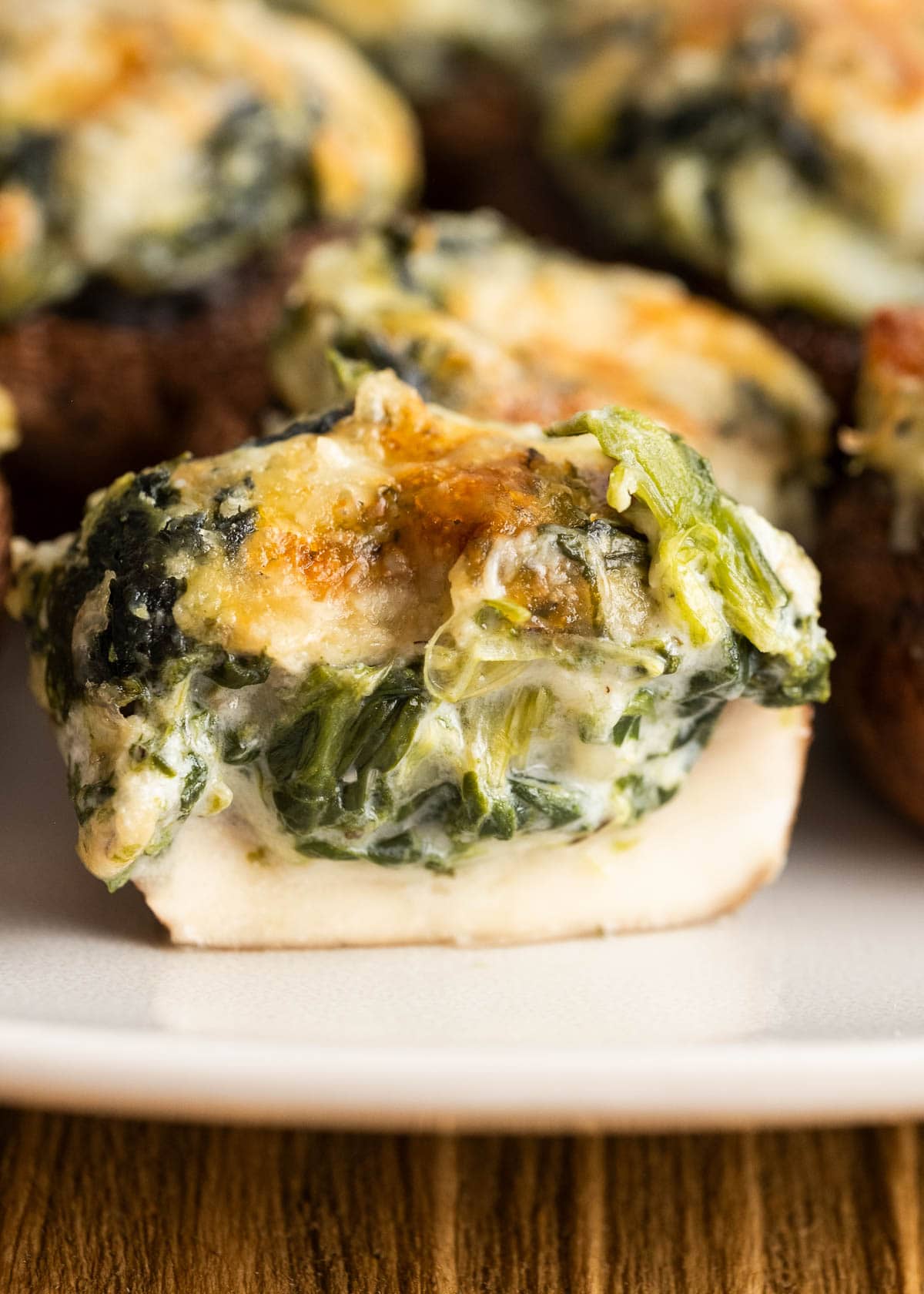 closeup of half of a spinach stuffed mushroom, showing the creamy cheesy filling inside a tender mushroom