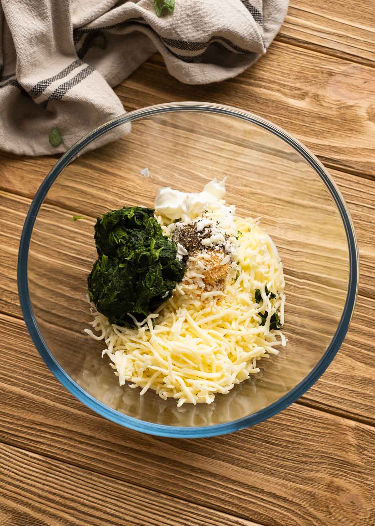 cream cheese, sour cream, shredded cheese, and spinach in a glass bowl
