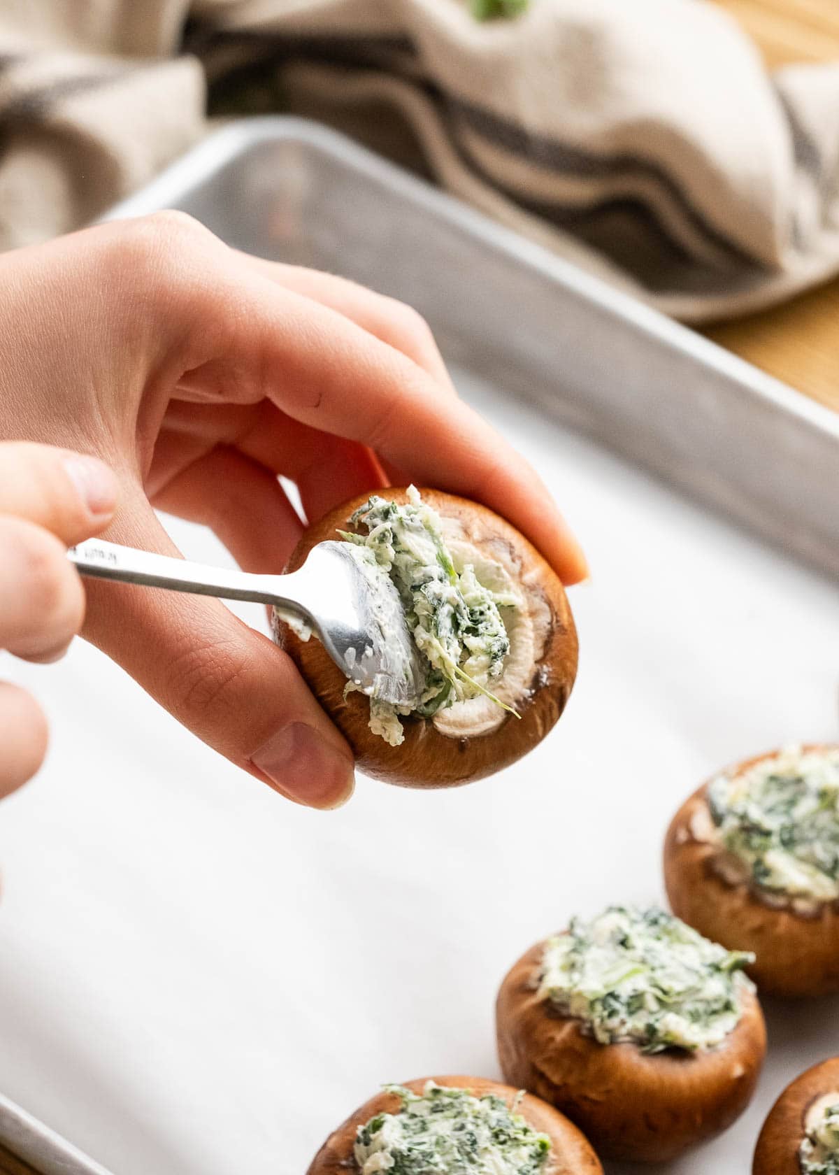 stuffing the mushrooms with the cheesy spinach mixture and placing on a lined baking sheet