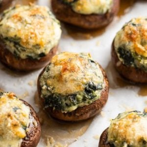 cheesy spinach stuffed mushrooms on a parchment paper lined baking pan
