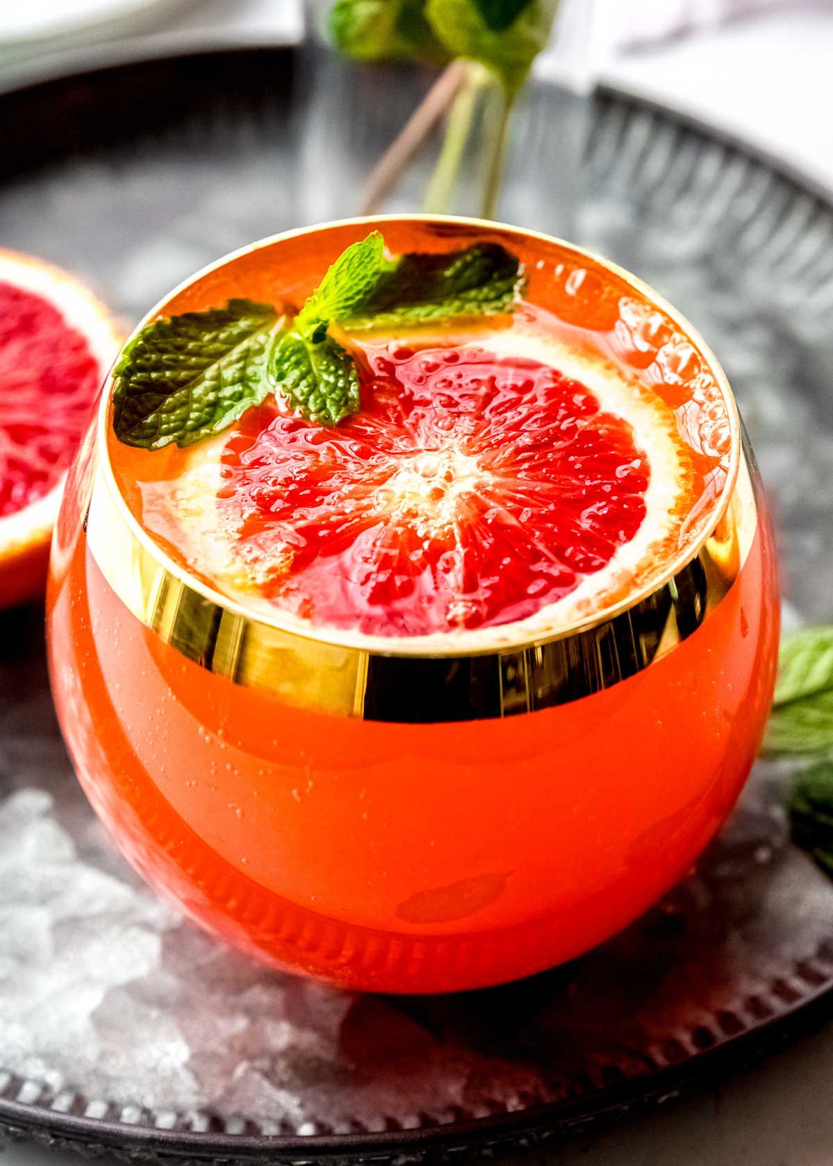 a close up shot of a blood orange cocktail recipe garnished with mint