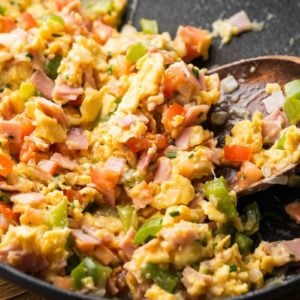 close up of loaded breakfast scramble being stirred in black skillet