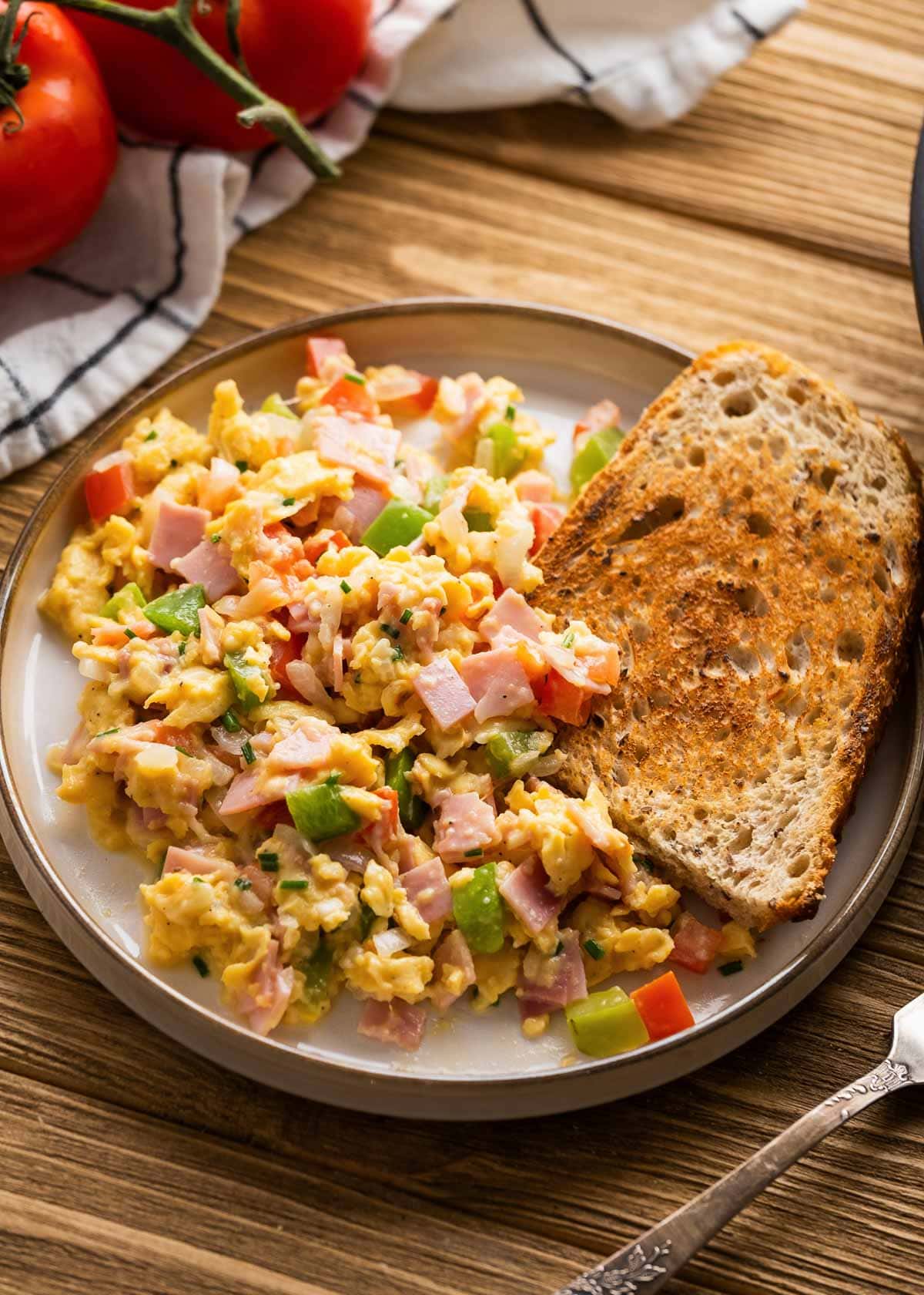 loaded breakfast scramble and piece of toast on white plate