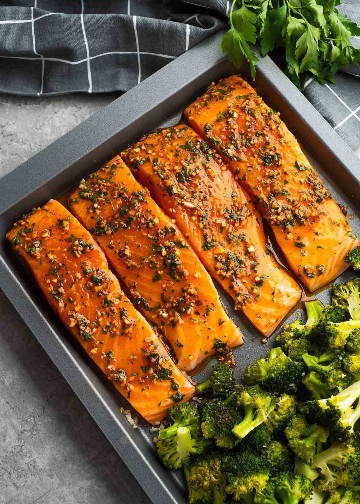 raw salmon filets and broccoli on a sheet pan