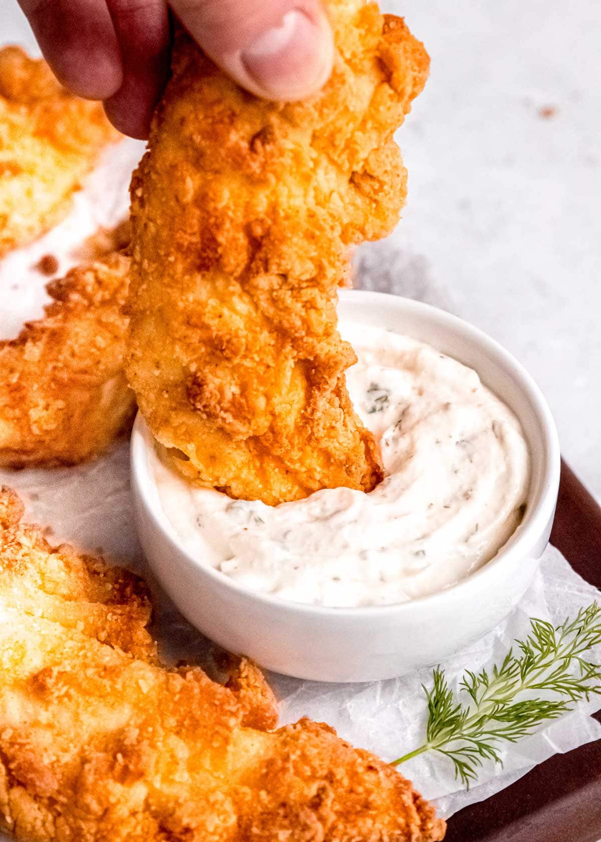 a crispy buttermilk fried chicken tender getting dunked into ranch dressing