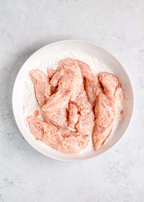 buttermilk marinated chicken in a shallow bowl with flour and seasonings