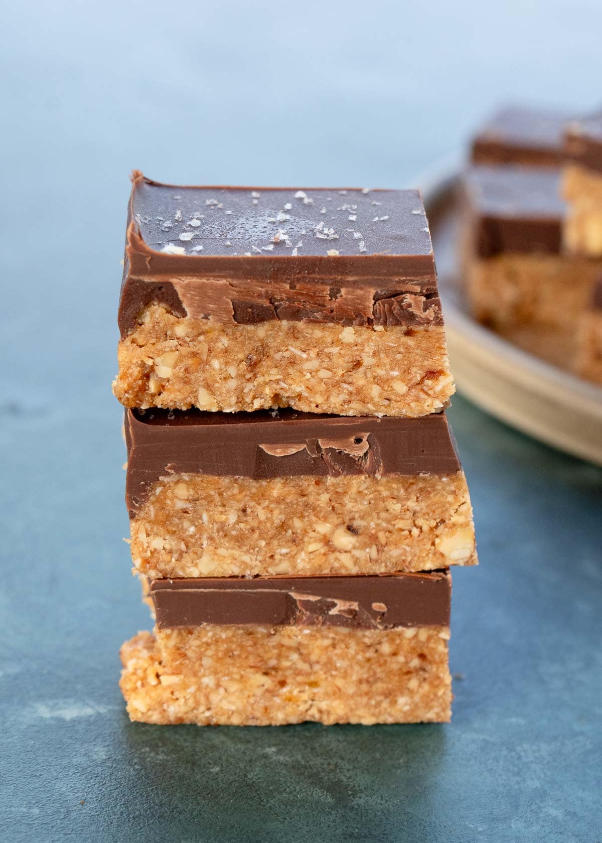 a stack of three no bake almond bars with thick chocolate layers