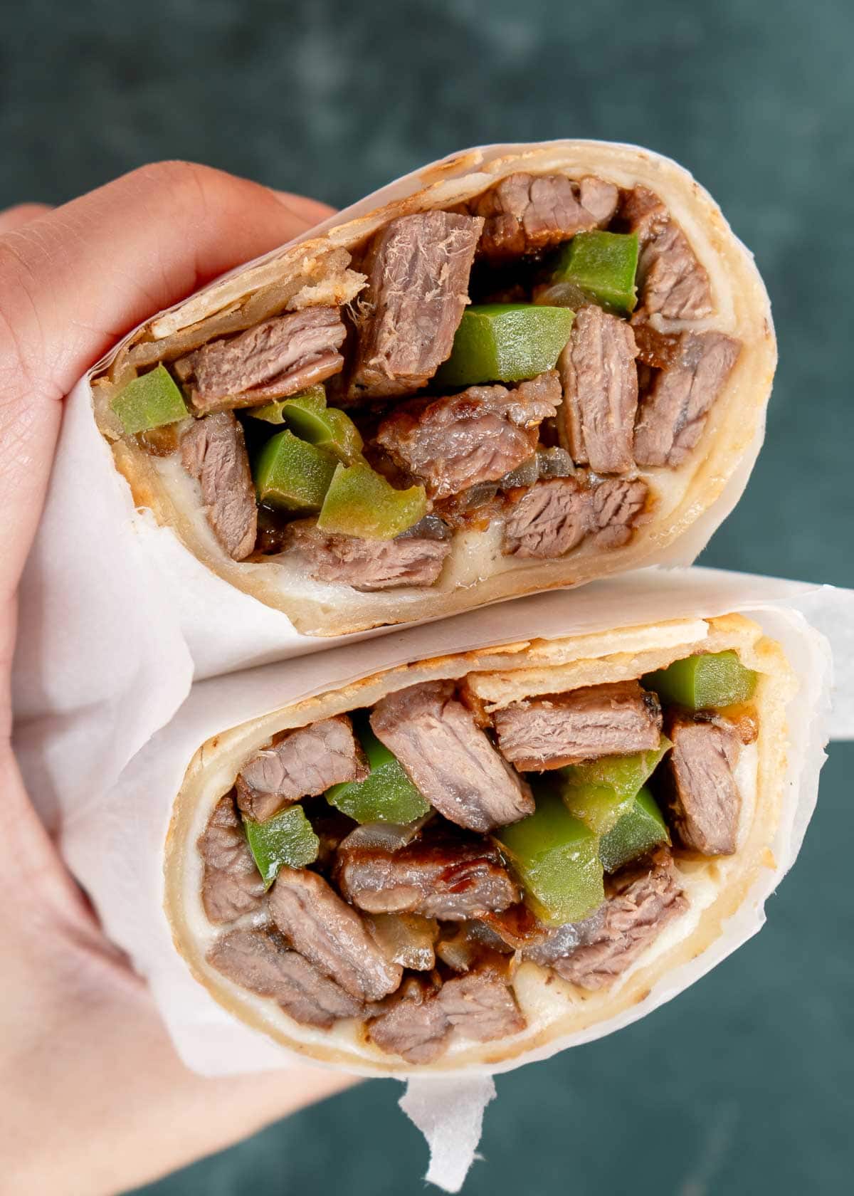 philly cheesesteak wraps with onions, peppers, and cheese in a tortilla