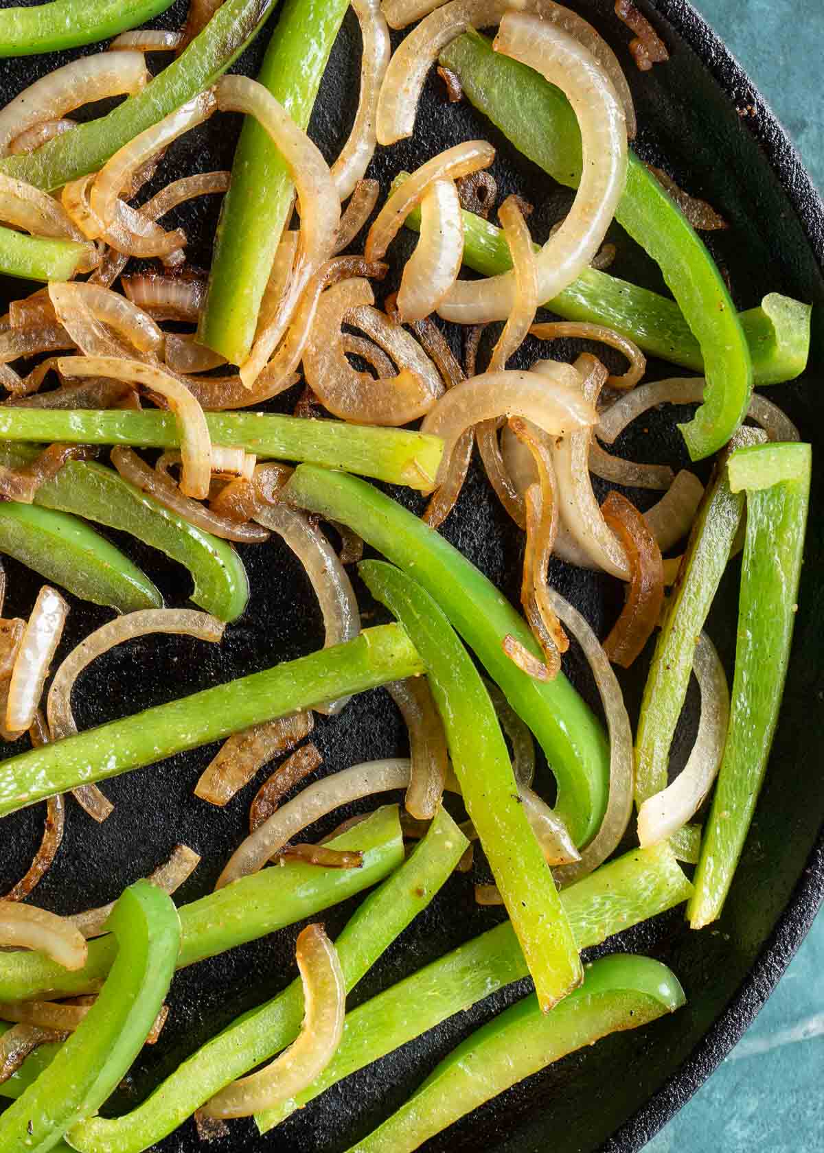 strips of onion and peppers cooking in a skillet