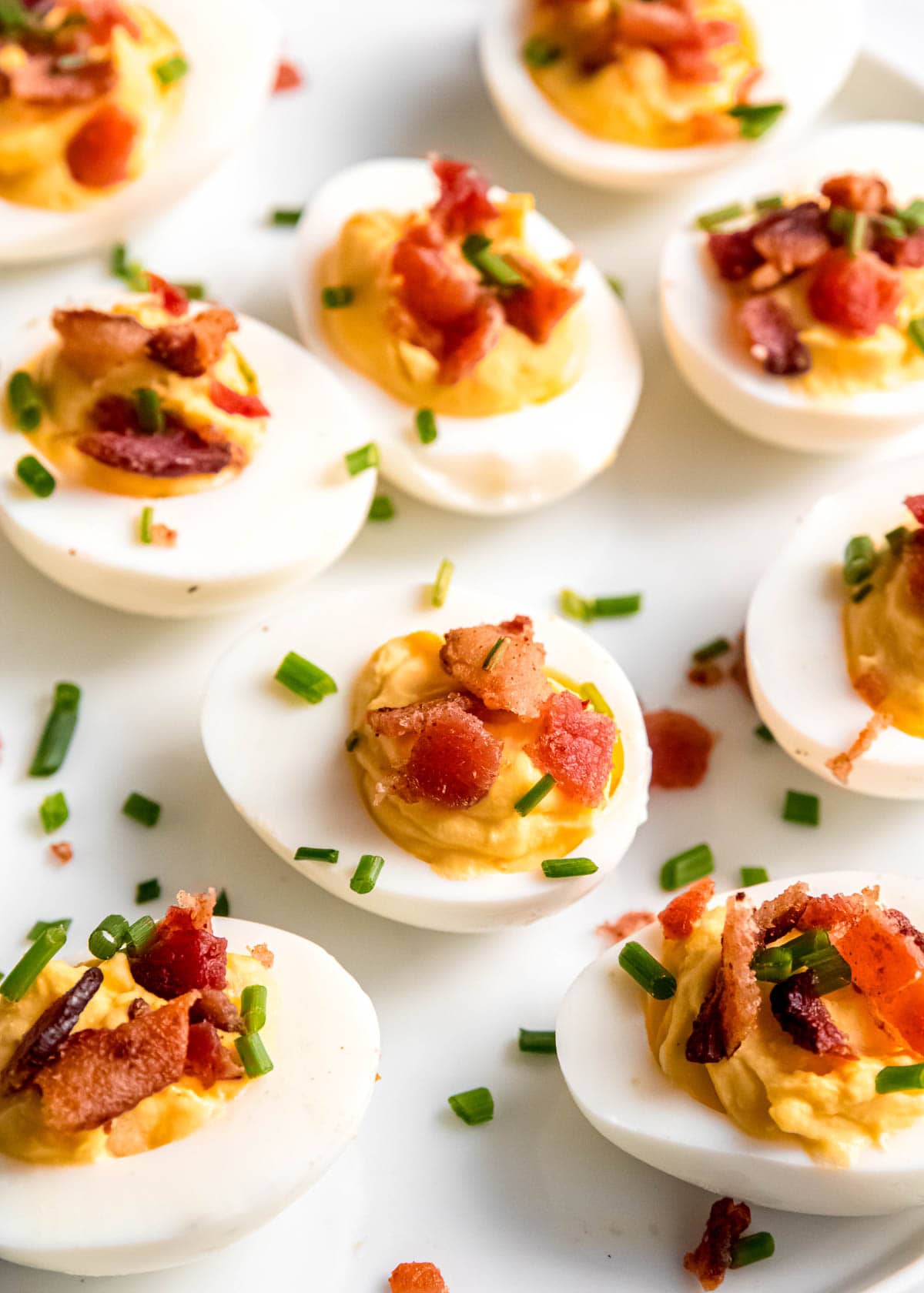 close up image of garnished deviled eggs on white platter