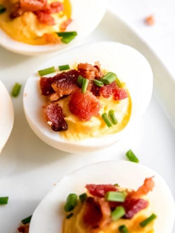 close up image of a single garnished deviled egg on white plate