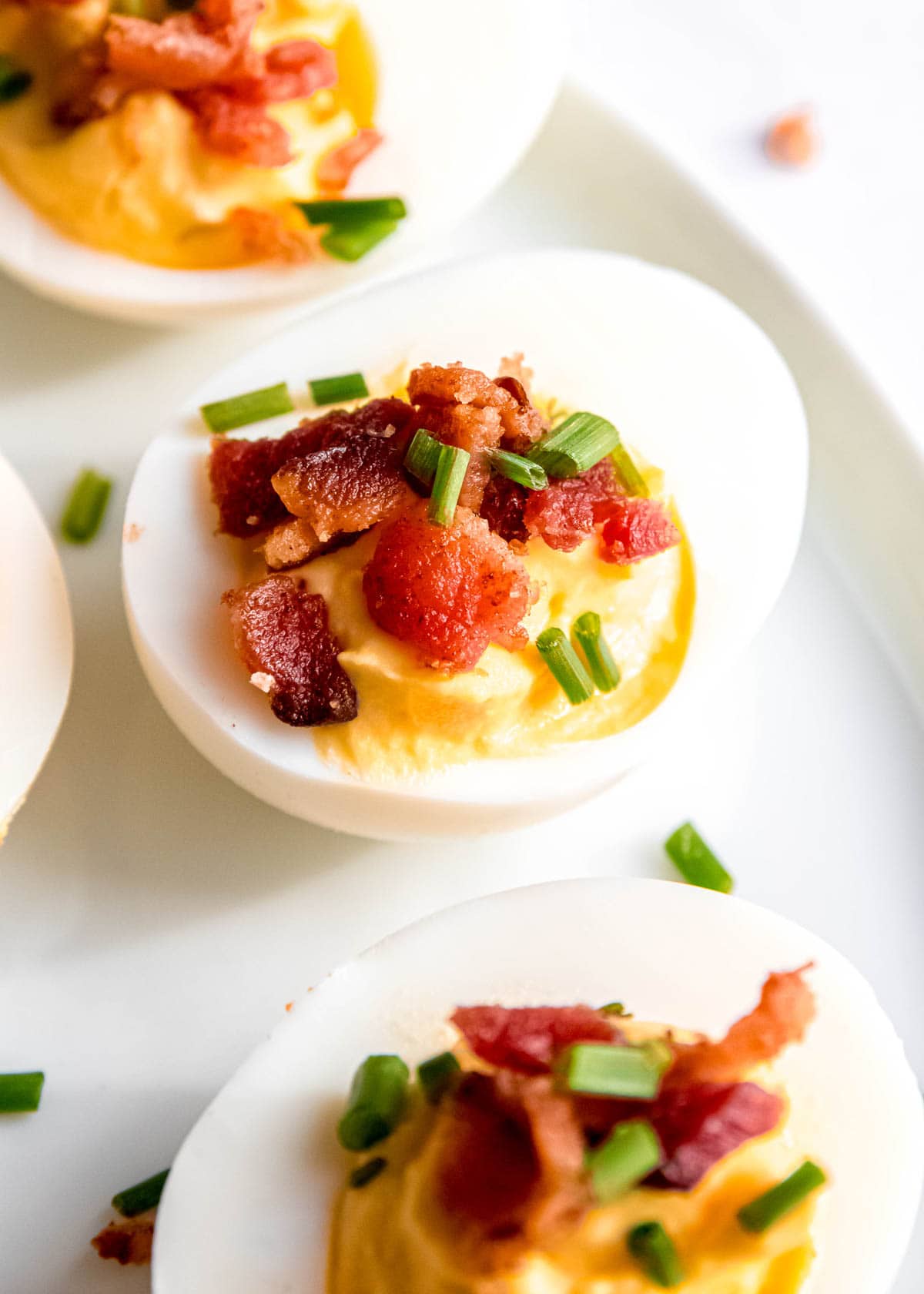 close up image of a single garnished deviled egg on white plate