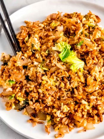 a white plate piled high with brussels sprout fried rice with chopsticks