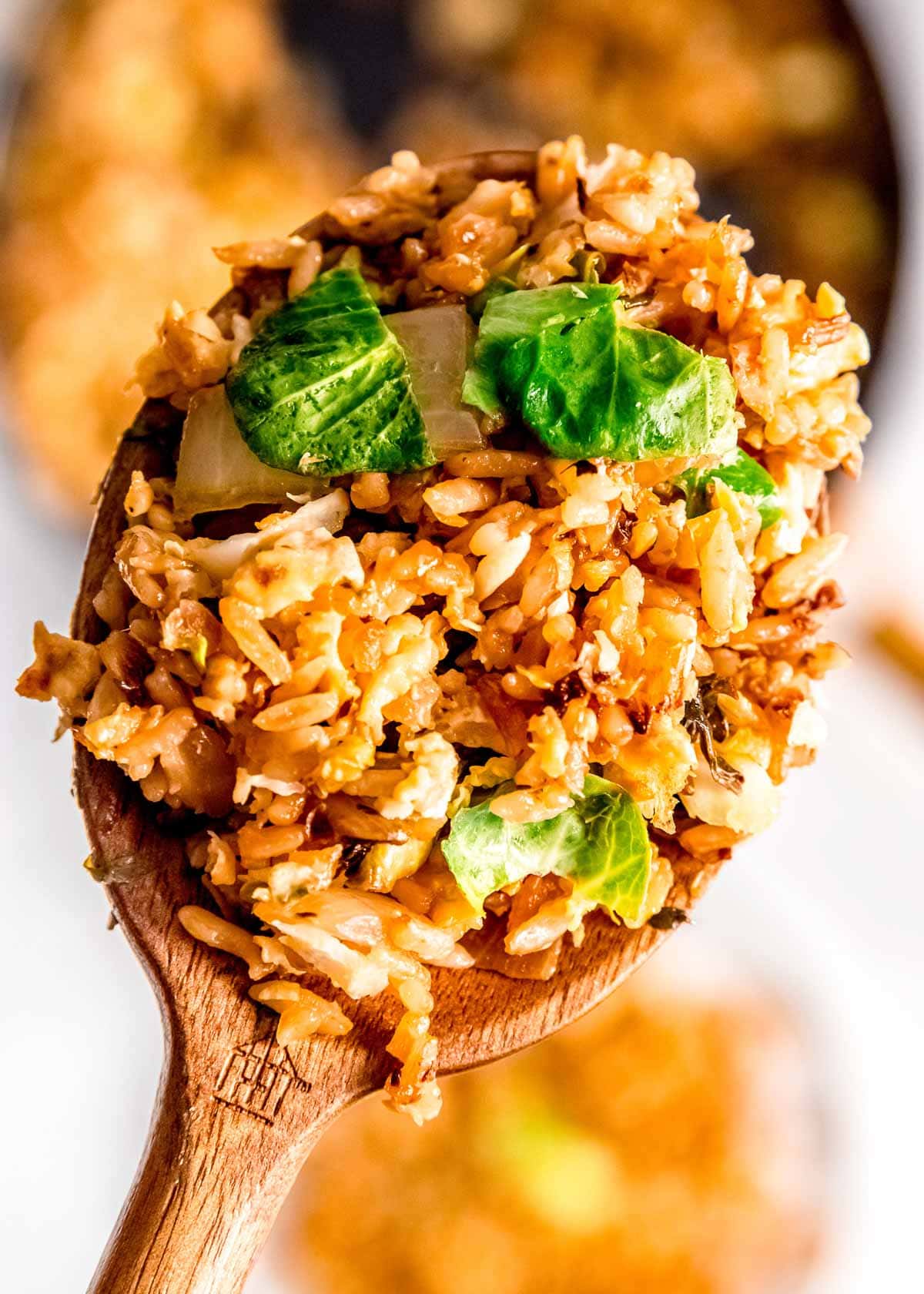 wooden spoon full of fried rice with crispy shredded brussels sprouts