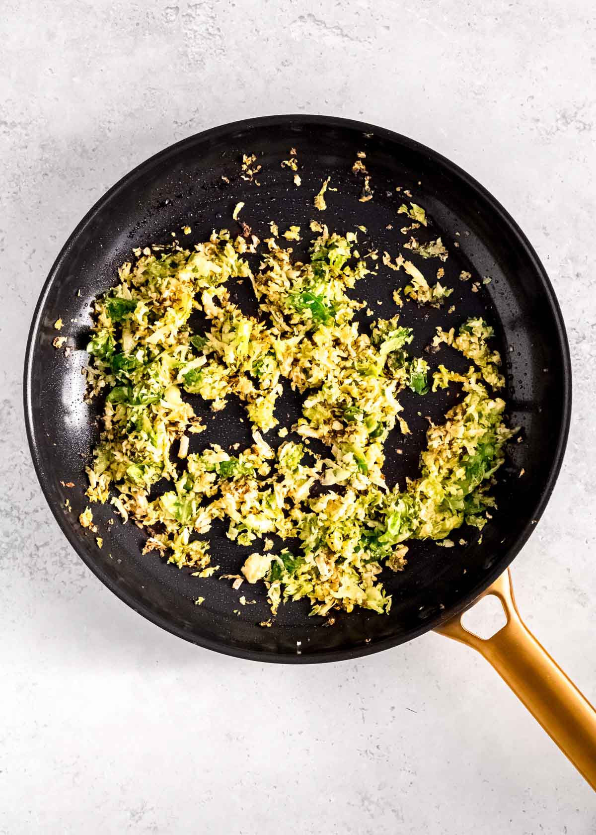 shredded brussels sprouts crisping up with sesame oil and garlic in a skillet