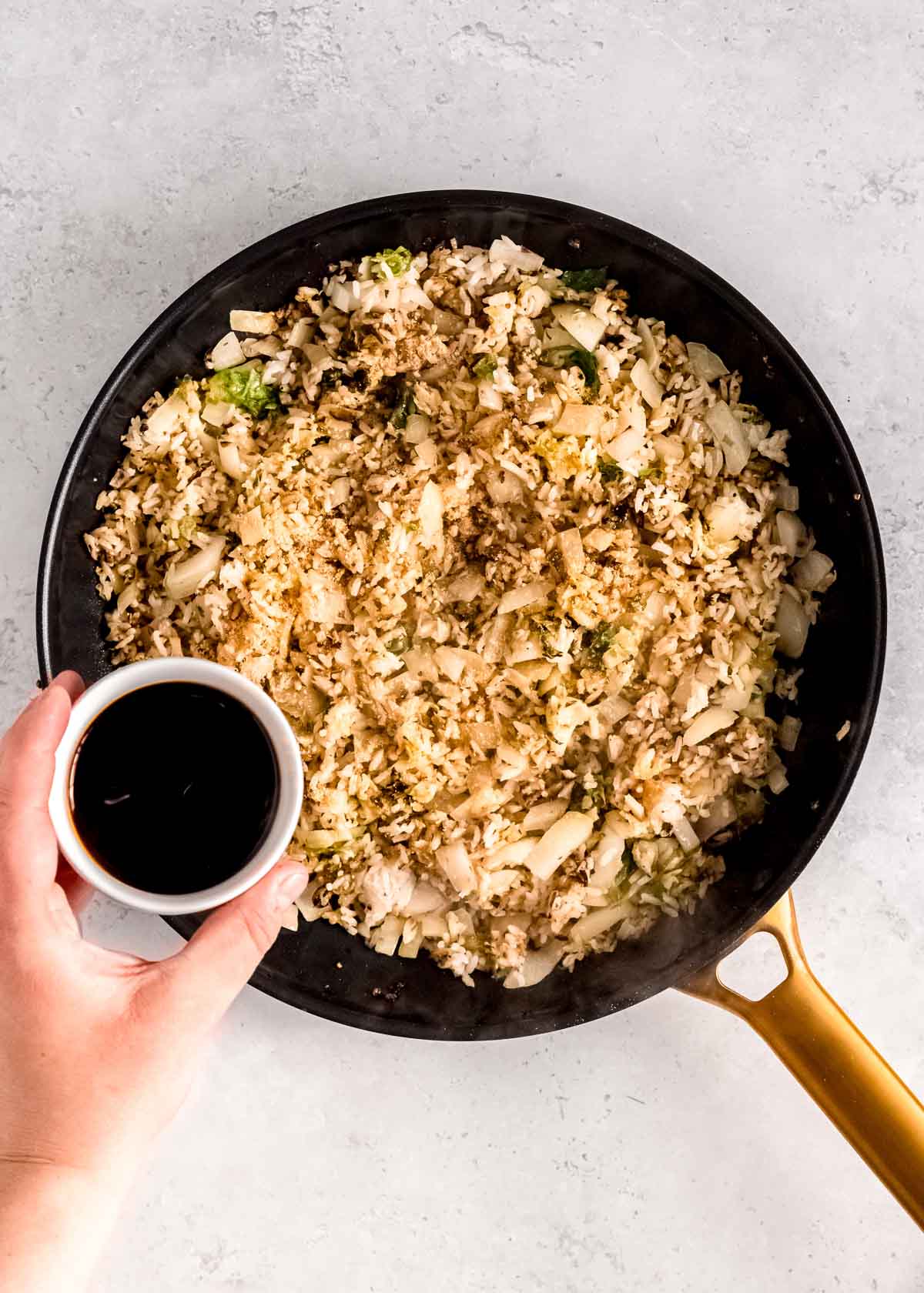 soy sauce being added to the fried rice with brussels sprouts, onions, and garlic