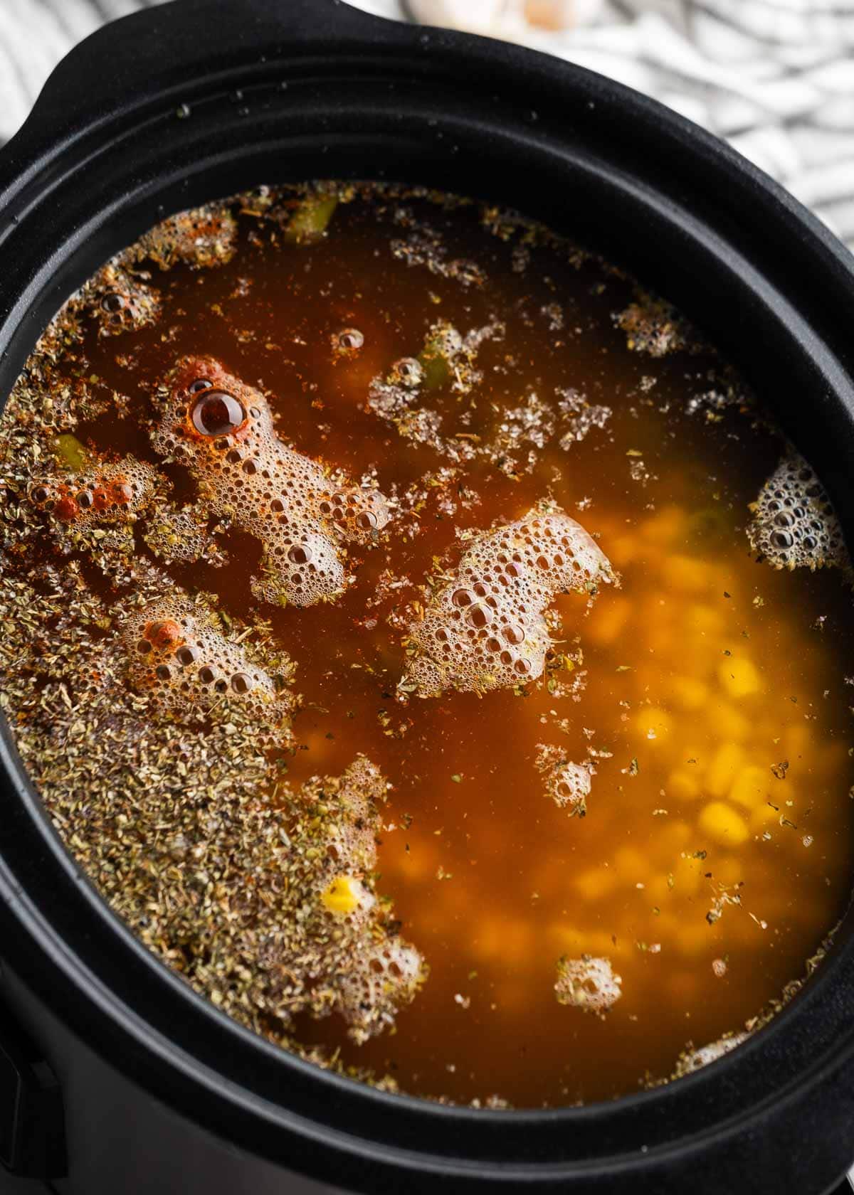 chicken, seasonings, and broth in a crock pot for enchilada soup