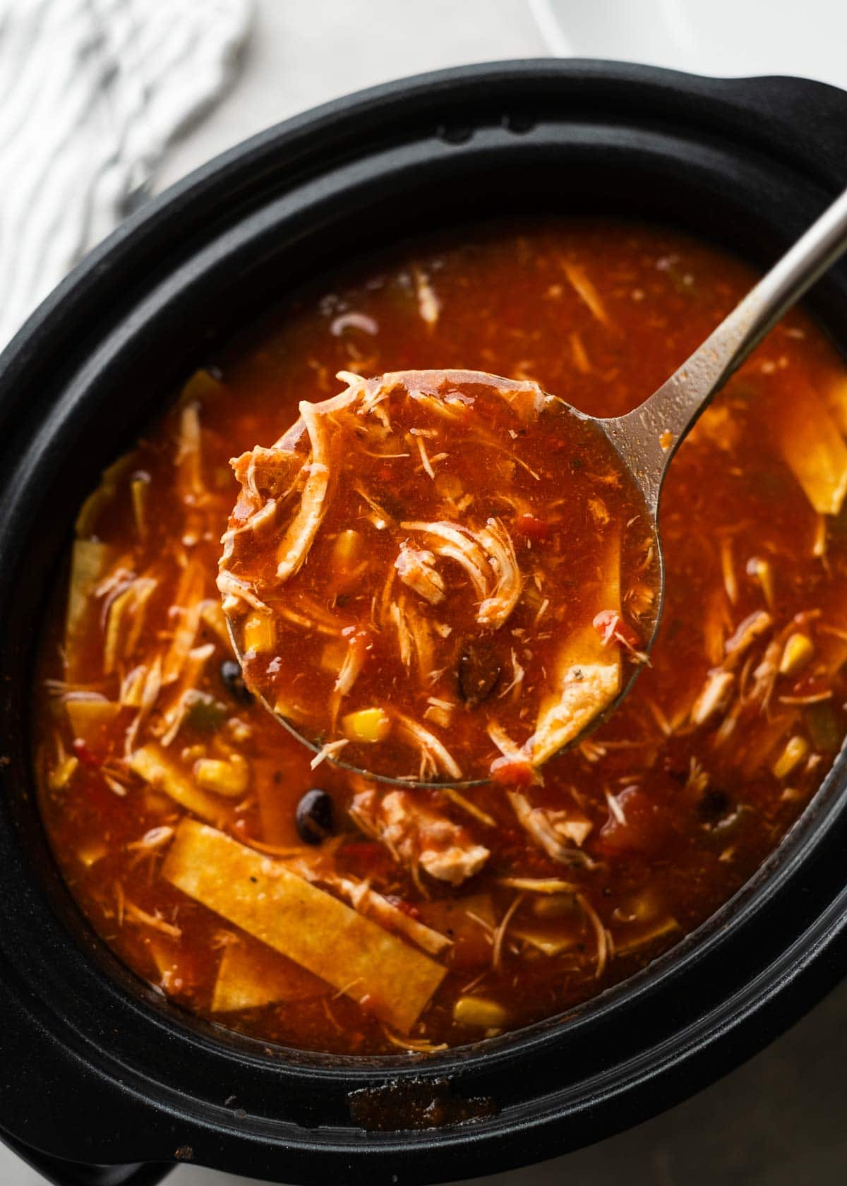 a crockpot and ladle full of chicken enchilada soup