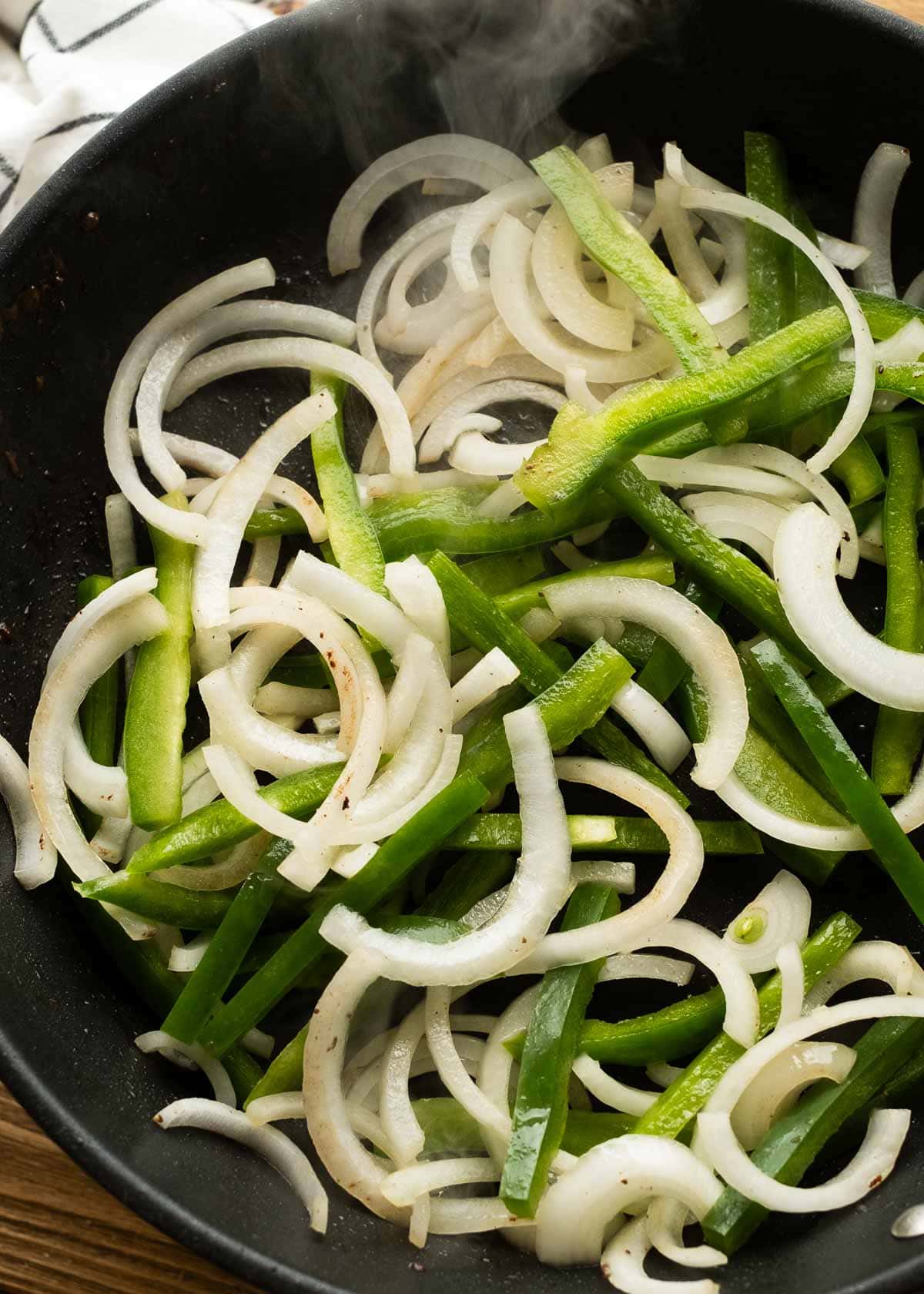 sliced onions and bell peppers in a skillet