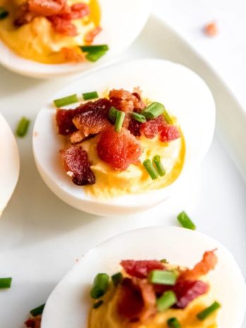 close up image of a single garnished deviled egg on white plate