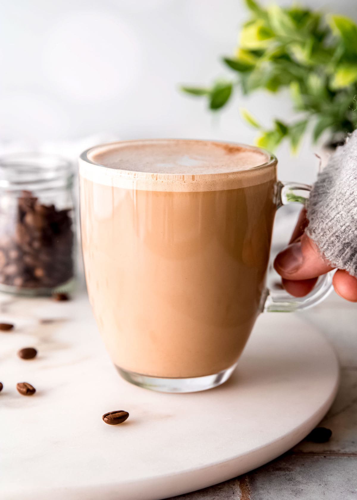 almond milk latte on white plate with coffee beans in background