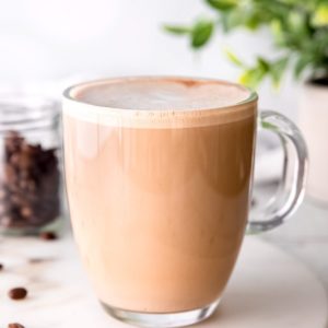 close up image of almond milk latte in clear coffee mug