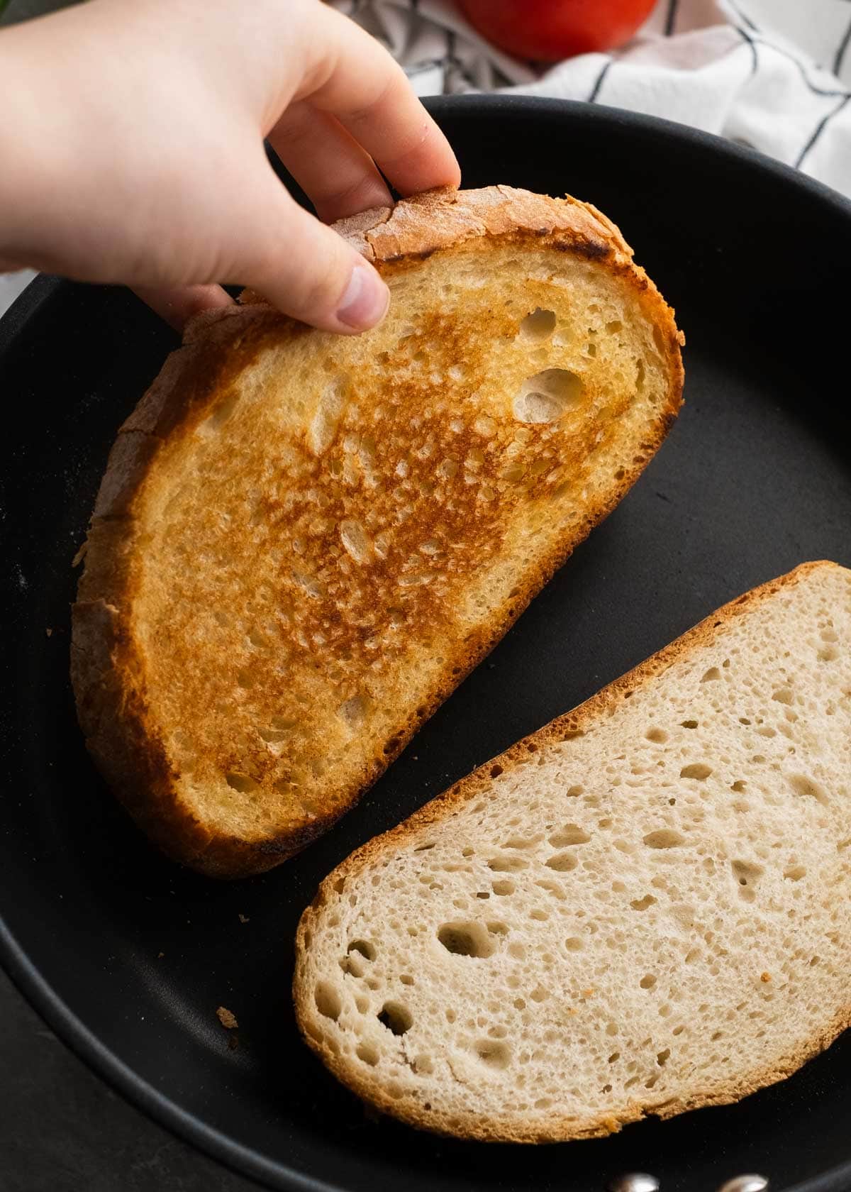 a browned slice of bread being removed from skillet