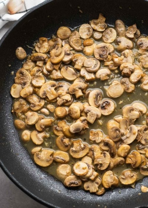 delicious sliced mushrooms and minced garlic in a skillet after simmering in white wine
