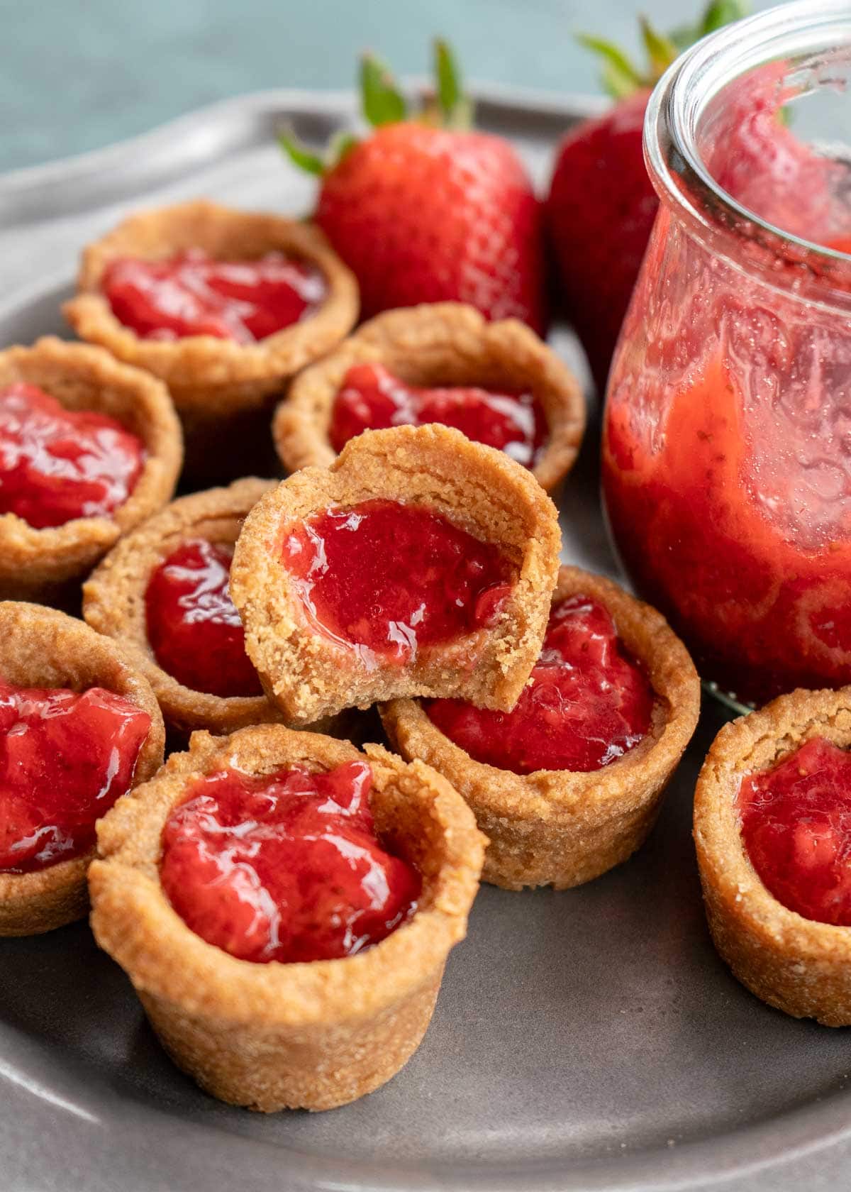 Peanut Butter and Jelly Cookie Cups on a platter with strawberries and a sugar free strawberry sauce