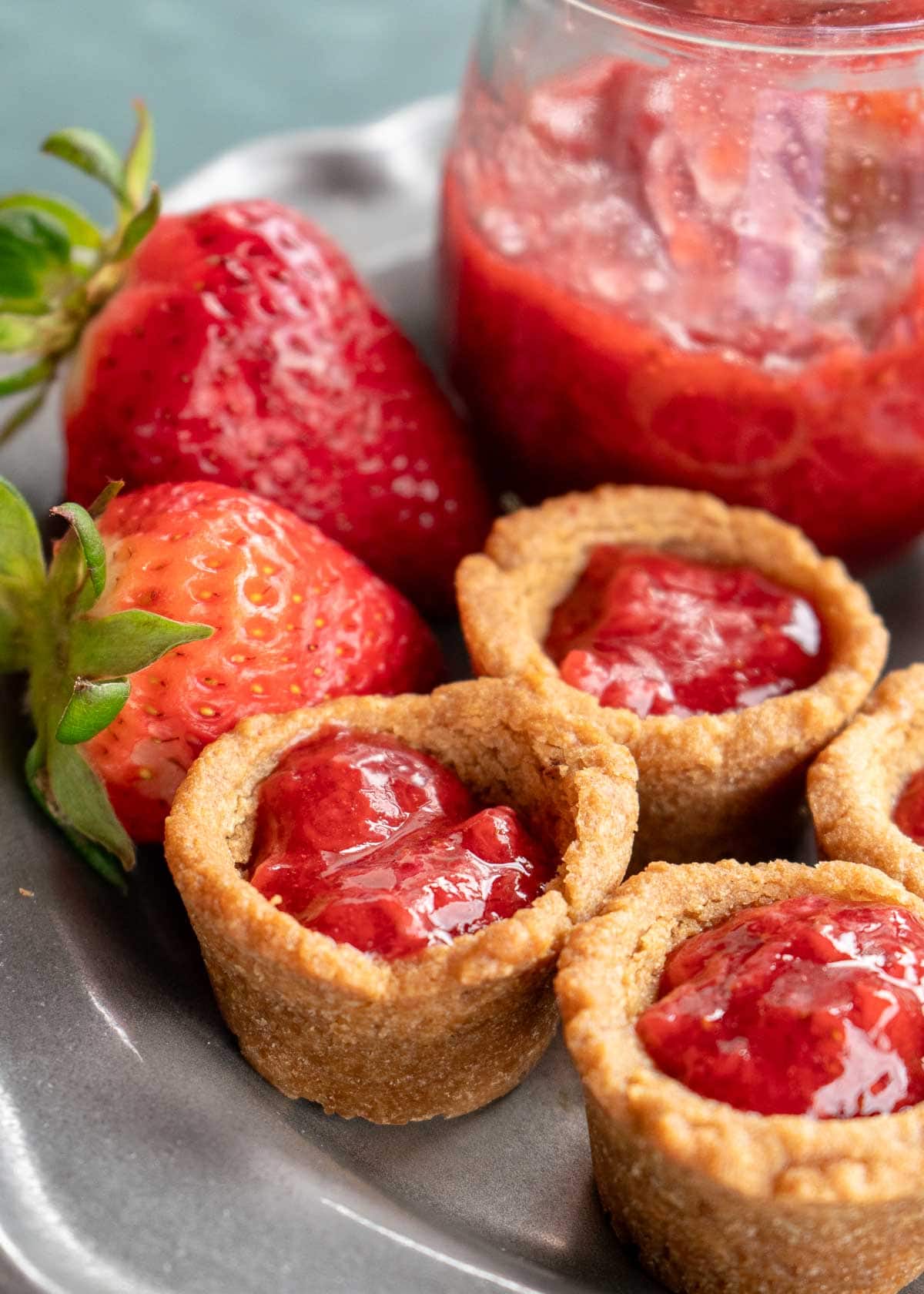 strawberries, sugar-free strawberry sauce, and peanut butter and jelly cookie cups on a plate
