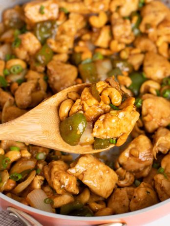 a spoonful of cashew chicken over a skillet full of cashew chicken